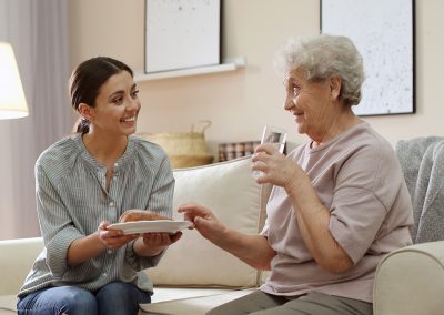 Woman and caregiver seated on a couch in her apartment